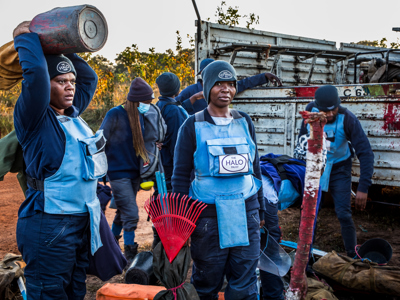 HALO deminers stand in front of a pick up truck carrying equipment around them