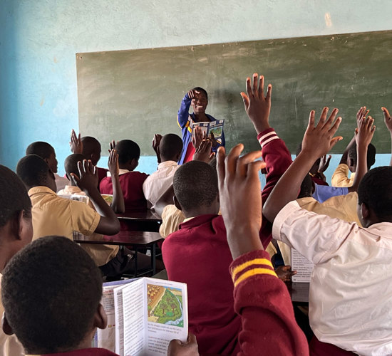 Children raise their hands in a mine education class
