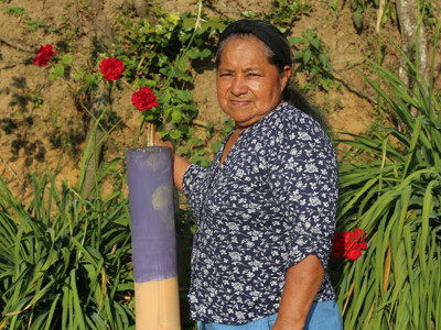 Landmine survivor, Alba Nelly poses outside with flowers and plants behind her