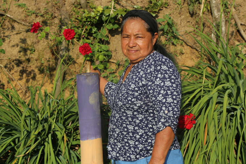Landmine survivor, Alba Nelly poses outside with flowers and plants behind her