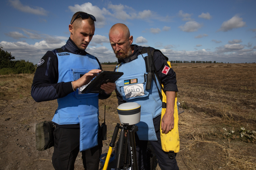 Two deminers work with a Trimble in a field
