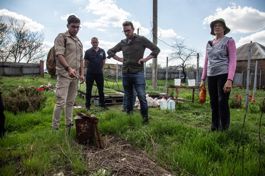 Natalia , a Ukrainian farmer, stands around a rusted bucket in her backyard with three other men 