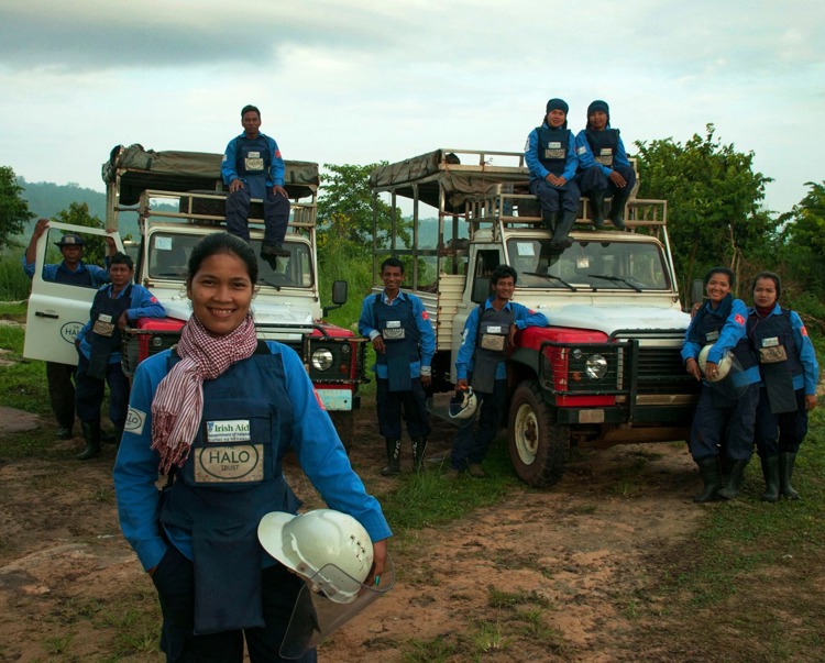 Deminers wearing protective gear pose with HALO vehicles 