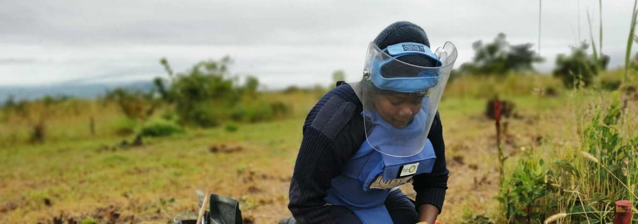 Female deminer wears PPE whilst carrying out demining activities on the ground