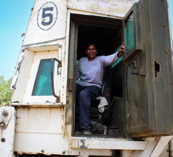 A female operator sits inside of a large mechanical vehicle 