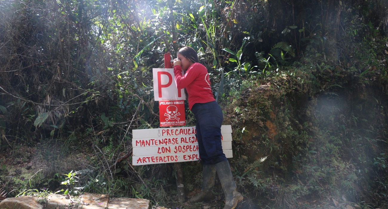 A HALO staff member checking a mine warning sign