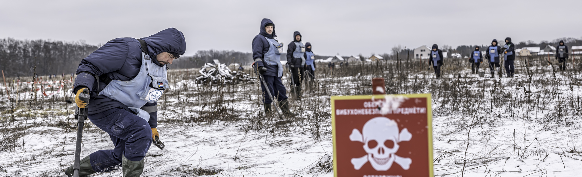 Deminers standing on a snowy minefield