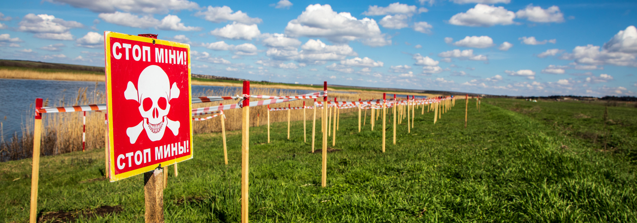 A minefield in Mykolaiv oblast is lined with mine stick markers and a mine warning sign
