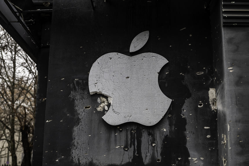 A damaged Apple logo hangs on the side of a building