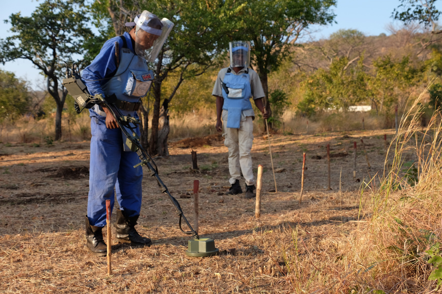 Deminers use detectors to scan mine marked ground
