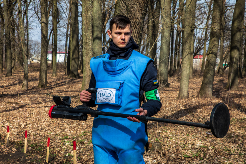 A Ukraine deminer holds a metal detector in a mine marked forest