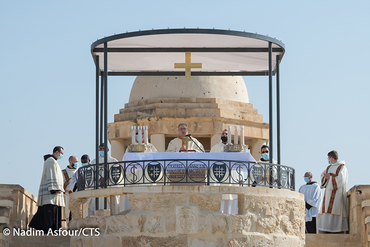 A priest and his alter servers stand around an outdoor alter