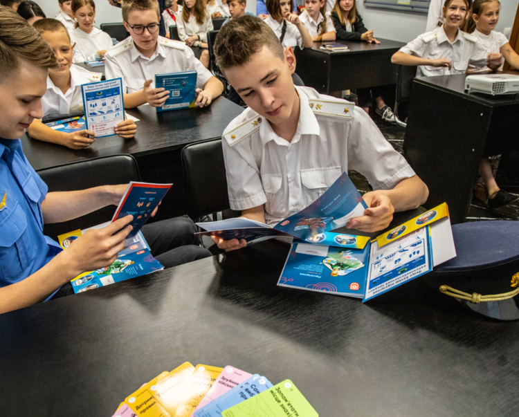 Kids in a classroom read through a mine risk education leaflet