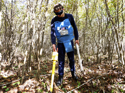 A deminer uses a Schonstedt Magnetic Locators in a forest
