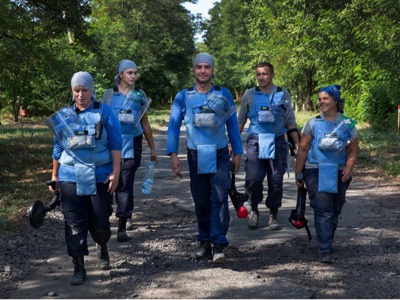 Demining Team in Zolotynka Village, walk down a path with their demining gear