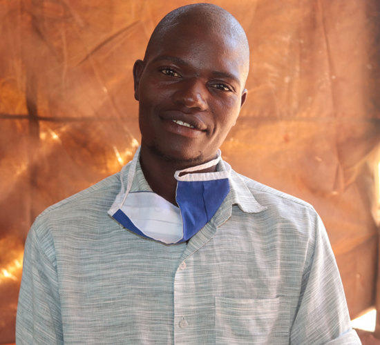 Prince, a landmine survivor poses in front of a brown background
