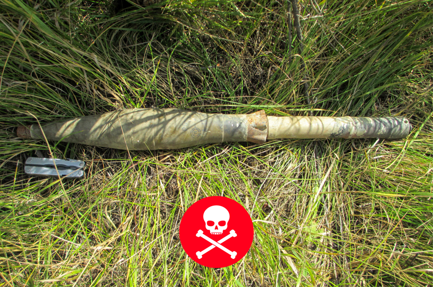 An unexploded ordinance lays on the concrete with a deadly warning logo in the picture