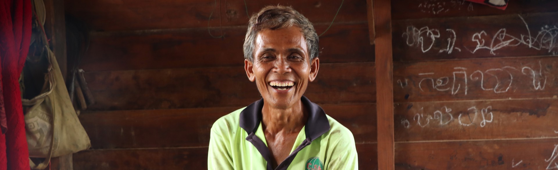Ouk, a farmer from Cambodia smiles while sitting on a bench