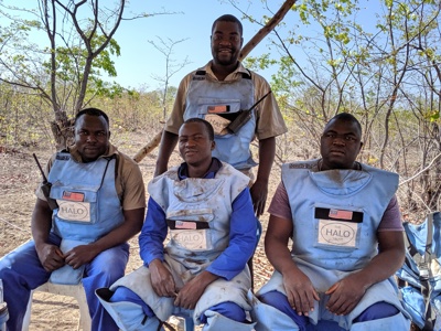 Deminers sit outside in their PPE