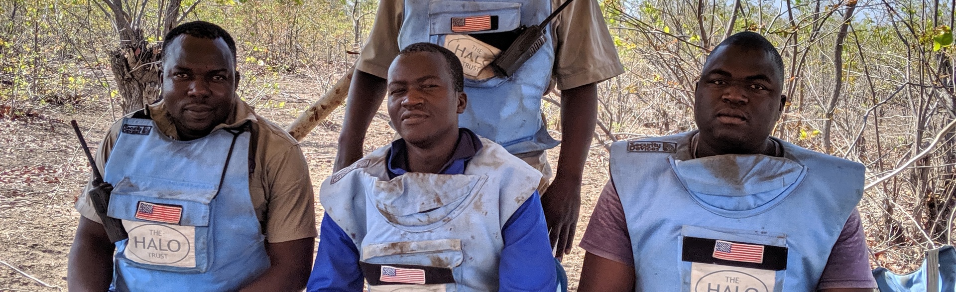 Deminers sit outside in their PPE