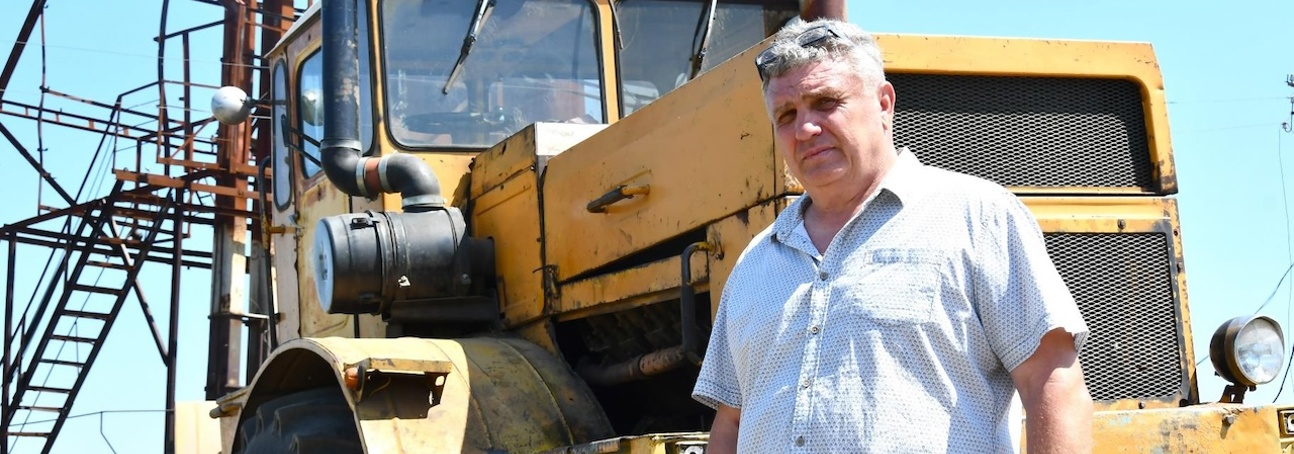 Serhii Kishkovskyi, a Ukrainian farmer stands in front of his farming vehicle in a field