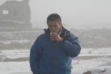 Tim Porter drinks from a mug outside in Afghanistan