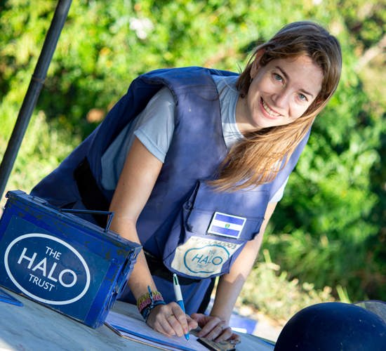 Maria wears a HALO vest as she writes on a clipboard