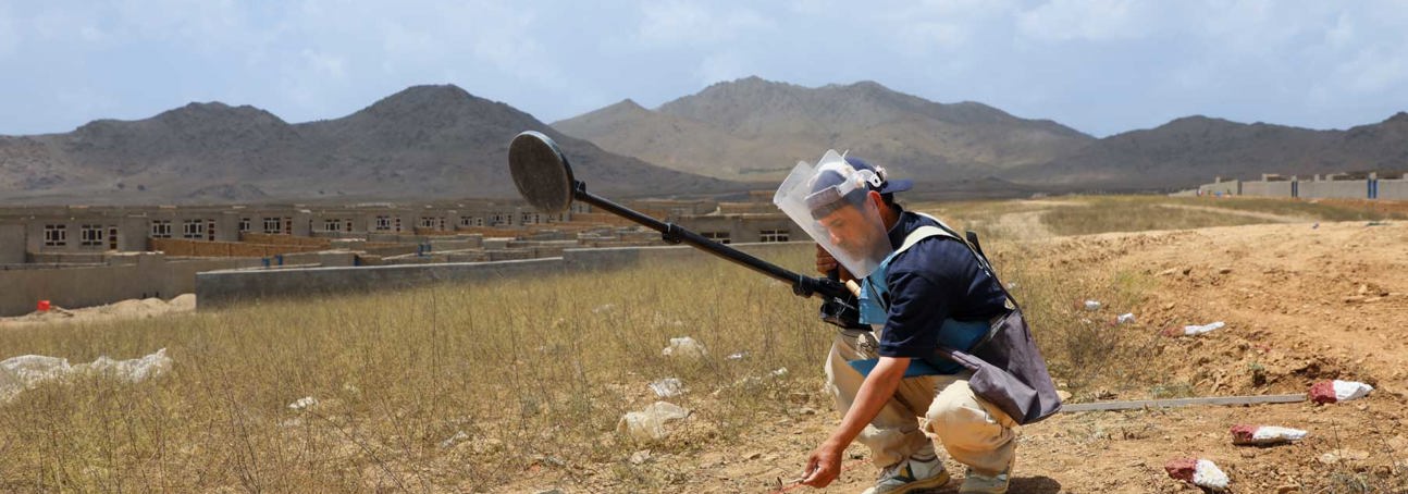HALO Trust deminer places a marker on the ground following the positive signal from a metal detector in a minefield in Afghanistan