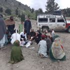 Residents of Khost gather round HALO medical professional as he treats a man on the ground