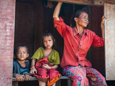 Ms. Xing and her two young children sit on a railing in Vangkhot village