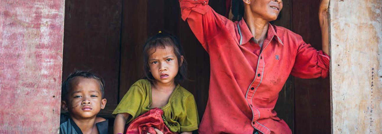 Ms. Xing and her two young children sit on a railing in Vangkhot village