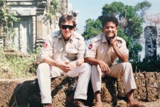 Tim Porter sits on a ledge with fellow Cambodian staff member
