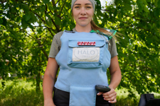 A female deminer in PPE poses with her metal detector