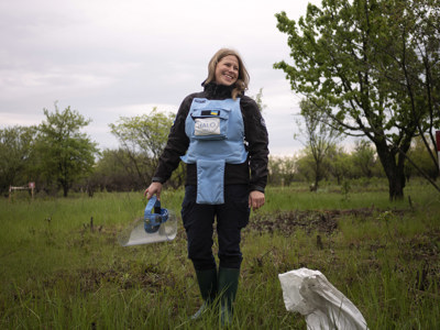 Ukrainian deminer smiling in the field while wearing PPE