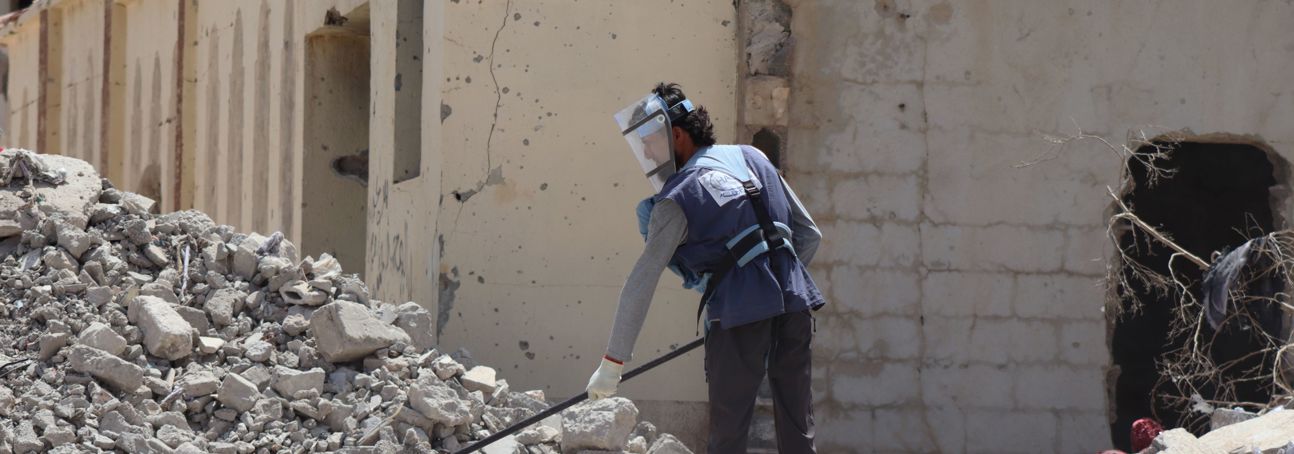 A HALO staff member wearing PPE and clearing rubble in an urban setting