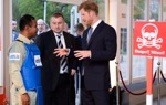 Prince Harry talks with a HALO Trust staff member wearing a protective vest near a display minefield at an event