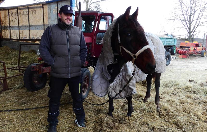 Volodymyr, stands with his horse and a tractor behind them