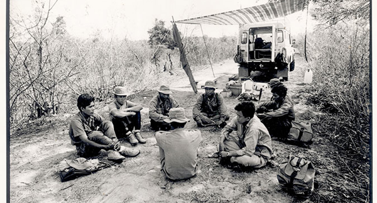 A black and white image of HALO Trust staff sitting down next to a tent during a break