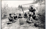 A black and white image of HALO Trust staff sitting down next to a tent during a break