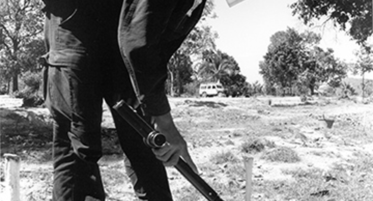 A deminer uses a small detector in a field in Cambodia