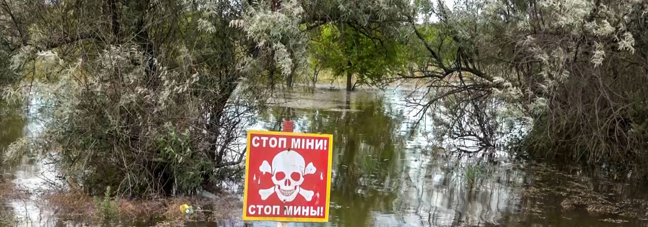 A red danger mines sign stands in front of the destruction of the Kakhovka Dam Flood