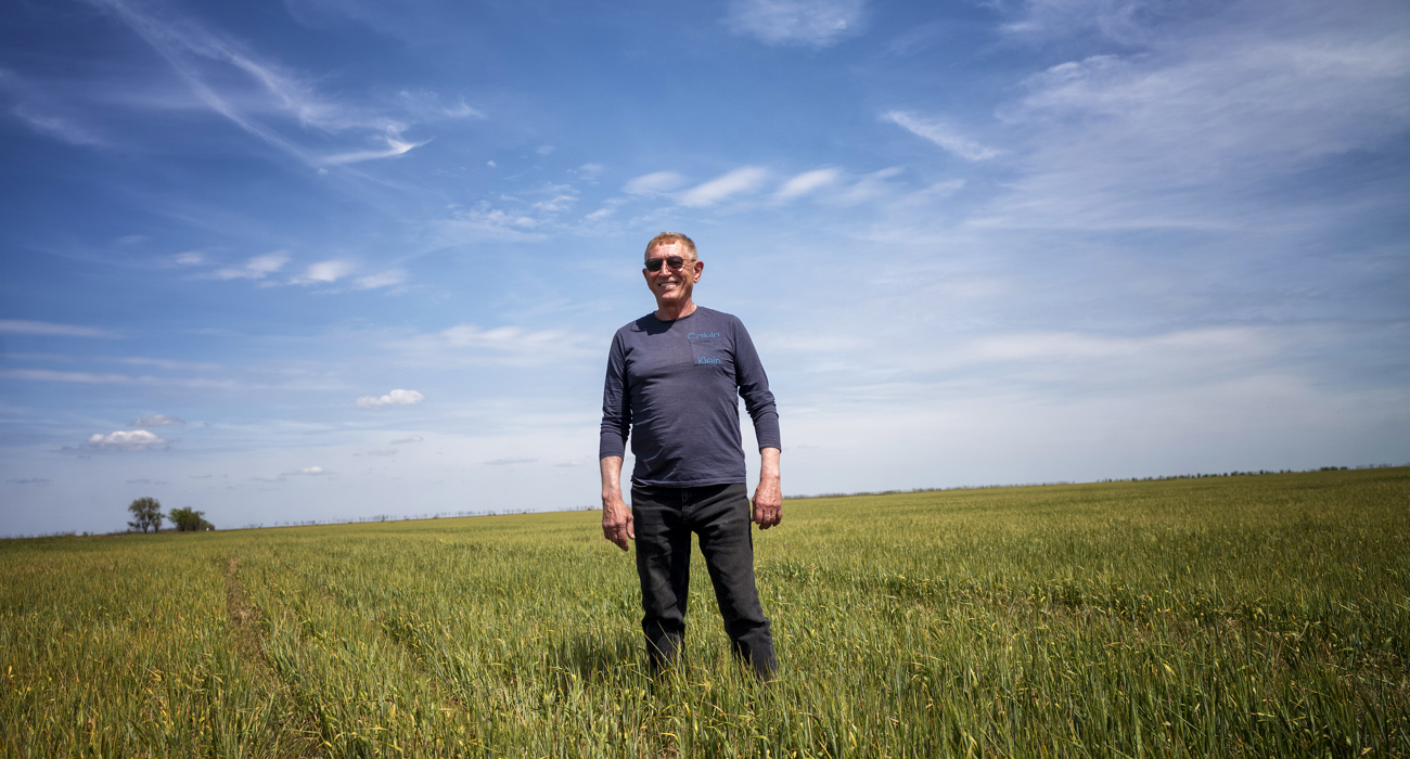 A man in sunglasses stands in the middle of a green field.