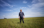 A man in sunglasses stands in the middle of a green field.
