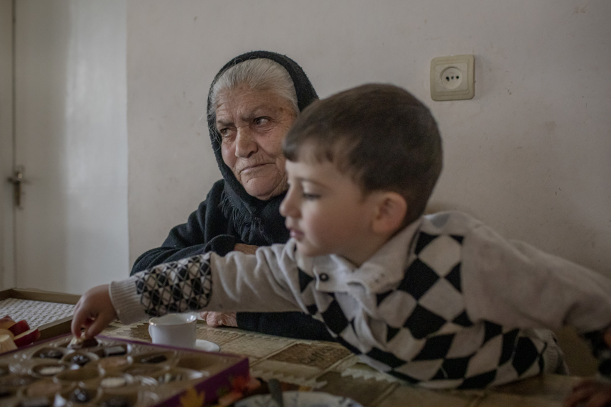 An elderly lady and her grandson sit at a table together