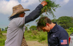 A woman drips water from wet plants above a US staff members head