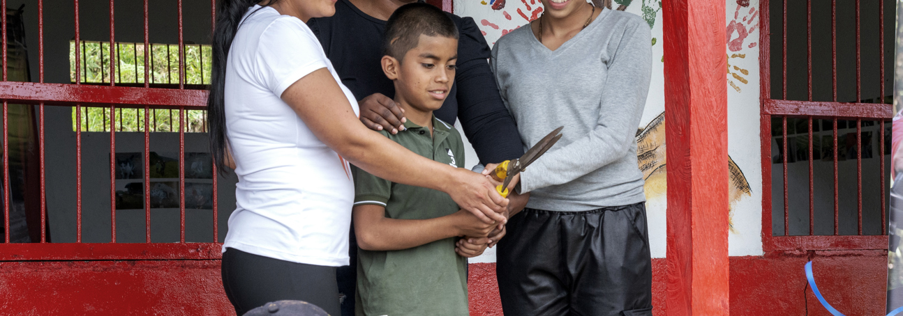 Group of adults and children cutting the ribbon to reopen Mesones School