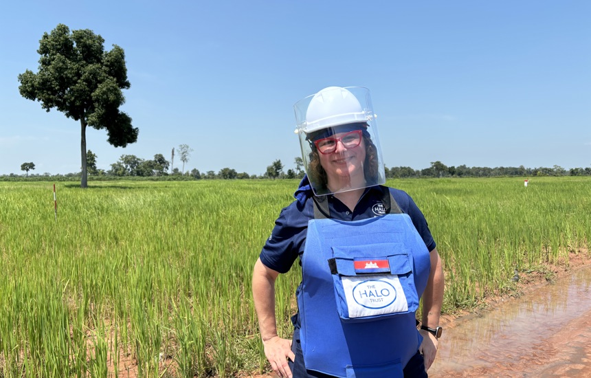 HALO staff member standing in a field in Cambodia wearing PPE