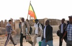 Pilgrims walk through the Baptism Site waving a flag