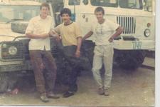 An old shot of Tim Porter and two other men standing in front of 2 large vehicles