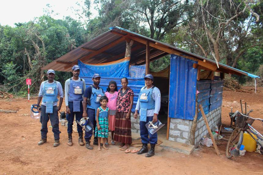 The Kirubayrani family stand outside a building with the HALO clearance team